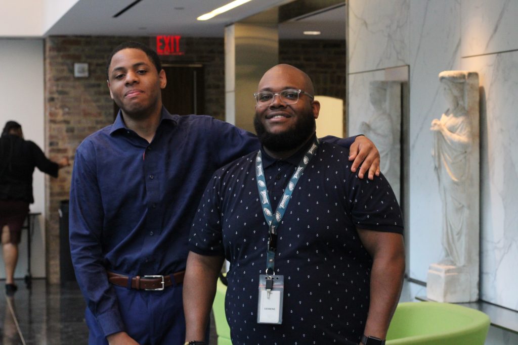 A student standing with his arm around his counselor's shoulders.